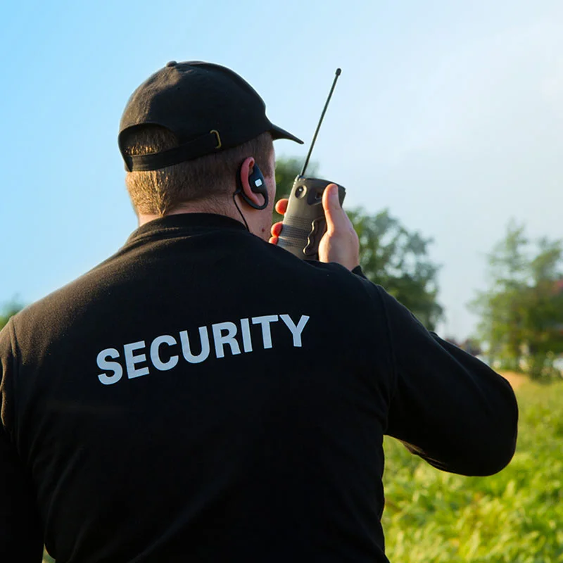 Ein Security-Mitarbeit steht im Freien und unterhält sich per Telefon.