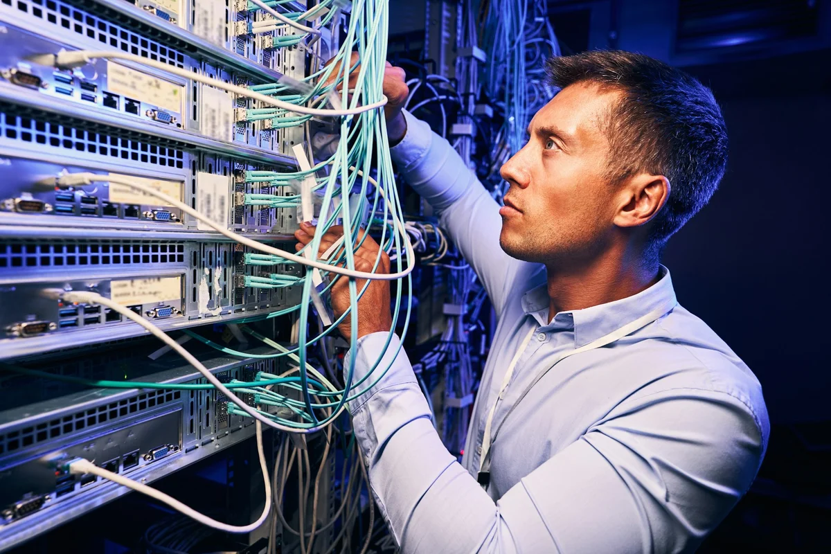 Ein IT-Experte überprüft den Server und die Verkabelungen.