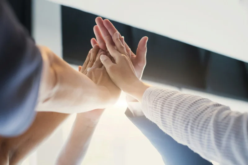 Gemeinsames Highfive von 5 Personen mit den Händen im Fokus 