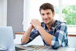 ein Mann sitzt an einem Tisch mit einem Laptop